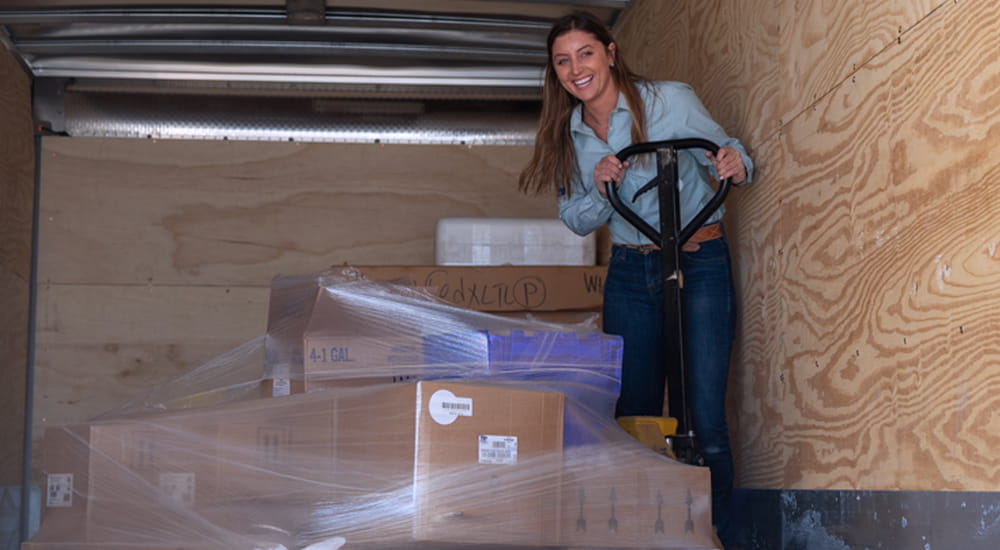 Woman using a pallet jack in the back of a truck